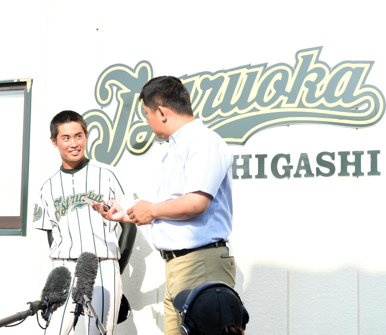 鶴岡東・佐藤監督（右）からネットニュースを見せられ、甲子園交流試合開催を伝えられた鈴木主将（撮影・山田愛斗）