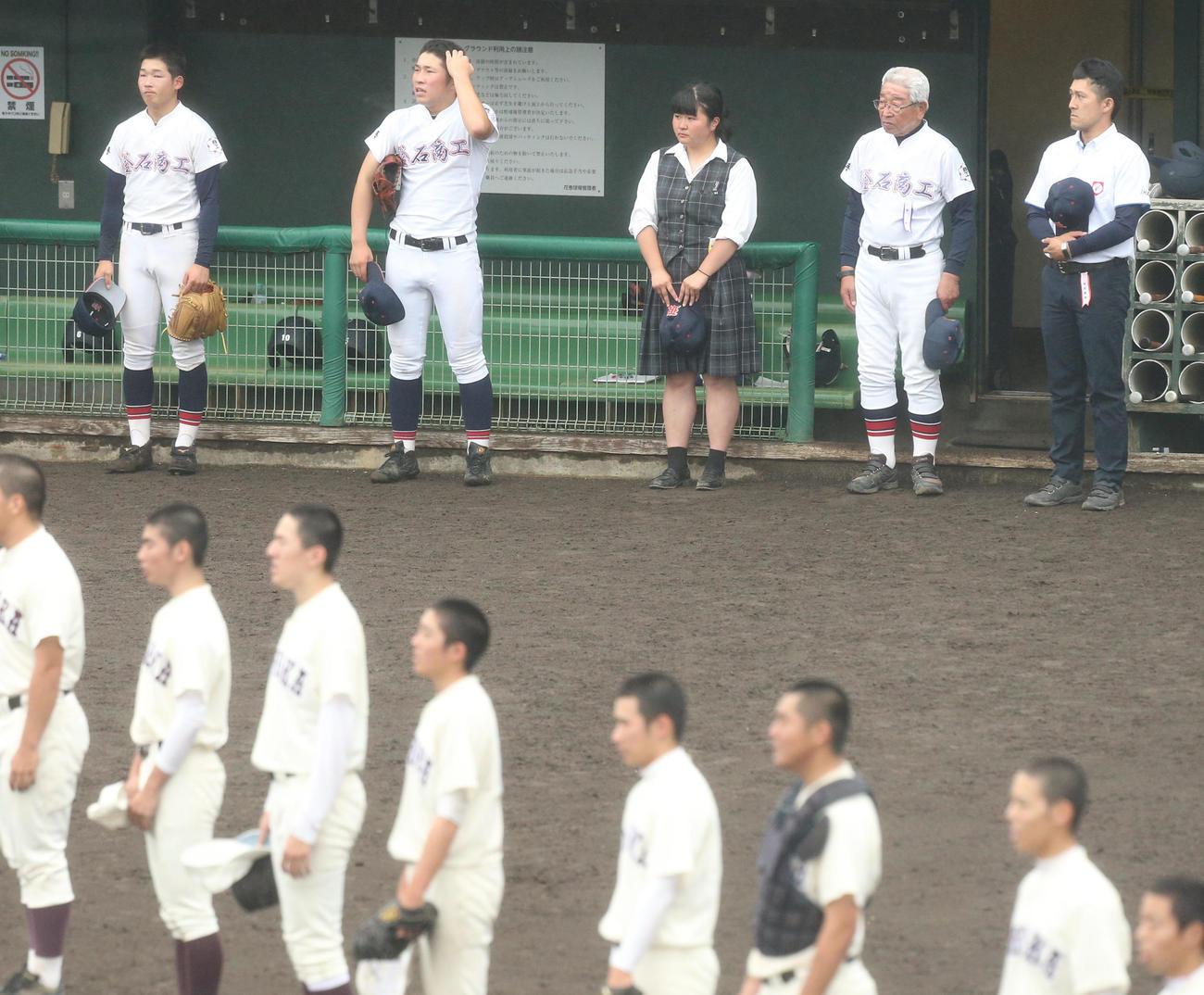 釜石商工対盛岡一　試合後に盛岡一の校歌が流れる中、ベンチ前に整列する左から釜石商工の山崎連、堀内主将、松田記録員、山崎善輝監督、伊藤部長ら（撮影・野上伸悟）