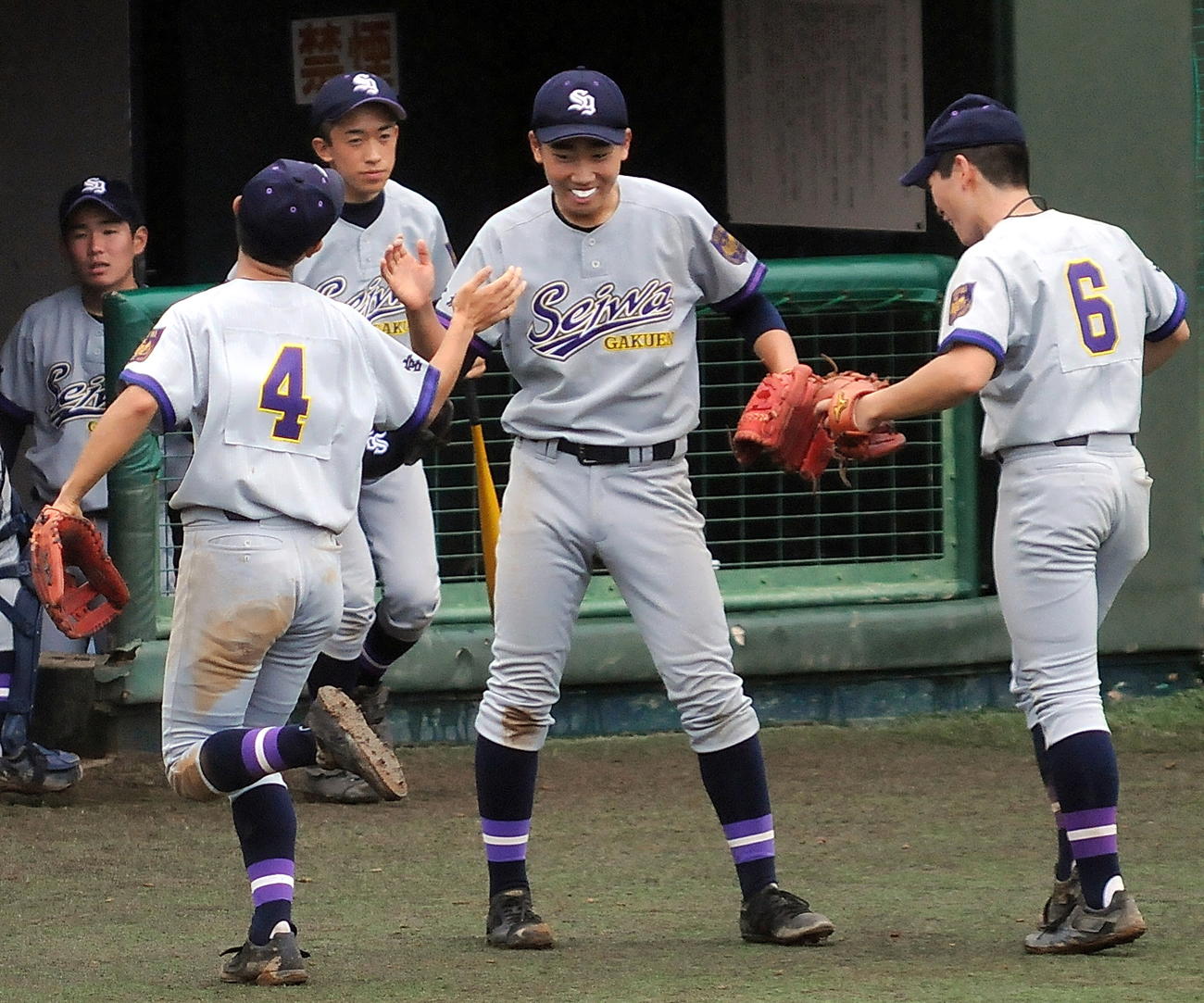 仙台三対聖和学園　7回表、聖和学園の2年生右腕・小林直生（中央）は三者三振に切り捨て、佐藤二塁手（左）と長谷川遊撃手の先輩野手2人とタッチをかわす