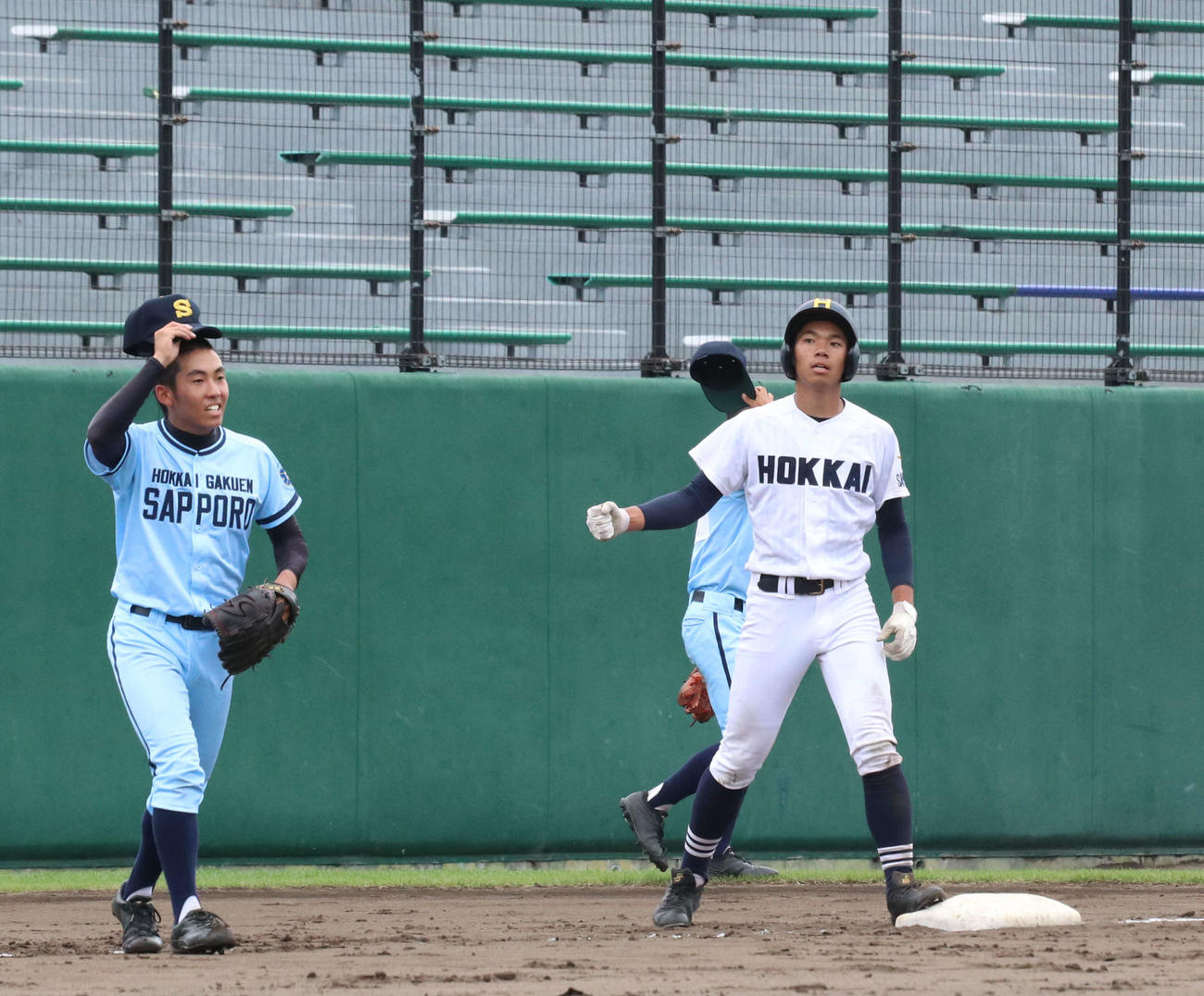 北海対北海学園札幌　8回表北海2死二塁、吉田は右越え適時三塁打を放ち、塁上で静かにガッツポーズ。左は北海学園札幌先発の佐々木（撮影・浅水友輝）