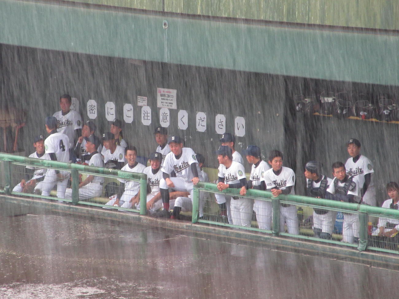 雷雨で中断中、ベンチで待機する吹田ナイン（撮影・加藤裕一）