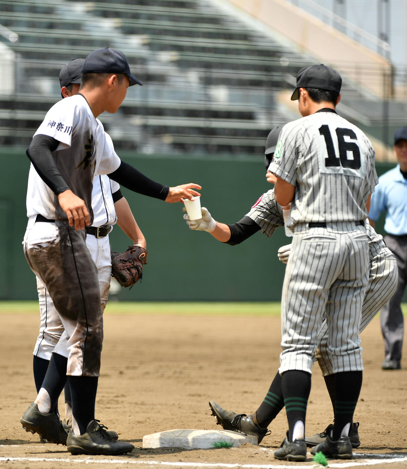横浜緑ケ丘対荏田　足がつった横浜緑ケ丘の選手に水を渡す荏田・堀岡（左）（撮影・横山健太）