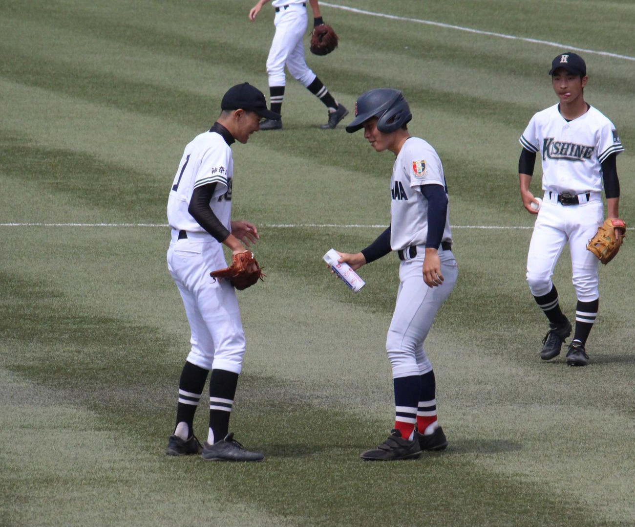 岸根対横浜　1回裏横浜無死、庄司雄大内野手の打球を右足に受けた岸根・市川（左）は相手の選手からスプレーをかけてもらう