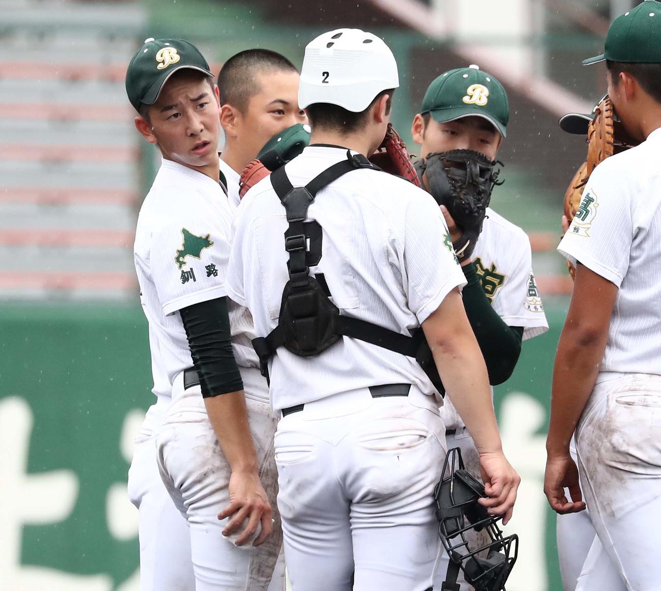 武修館対クラーク　ピンチでマウンドに集まり渋い表情の中谷（左）（撮影・黒川智章）
