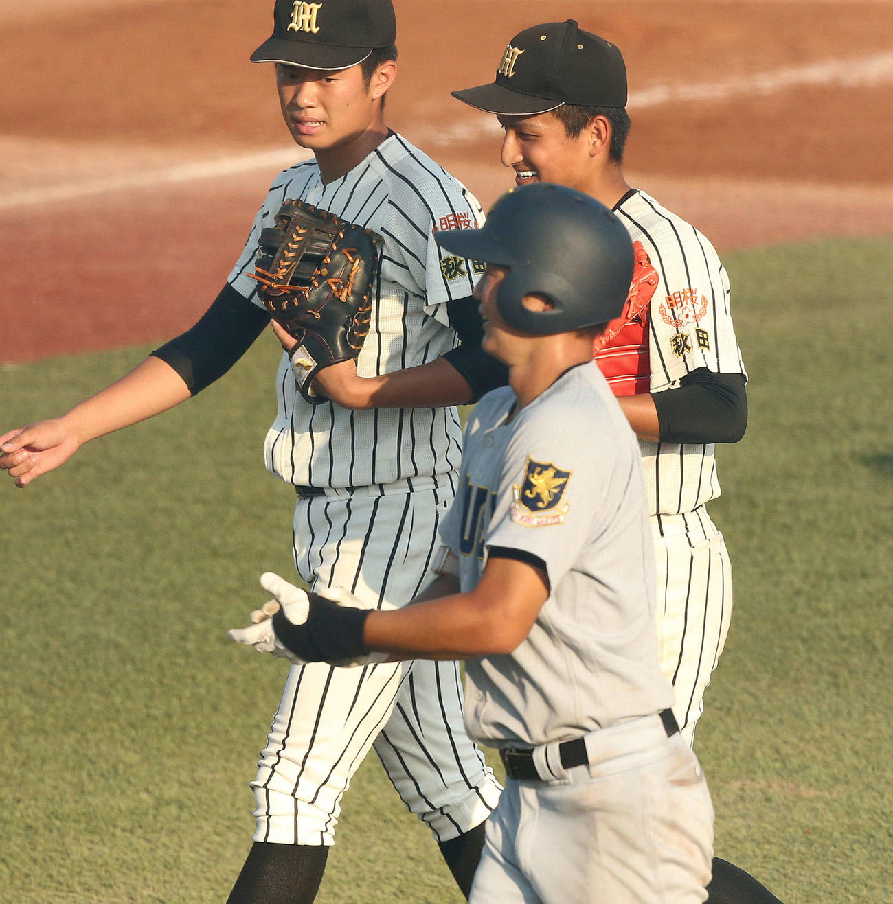 明桜対仙台育英　タイブレークの10回裏、仙台育英・宮本（手前）にサヨナラ打を浴びた明桜・長尾（奥右）は笑顔で引き揚げる（撮影・野上伸悟）