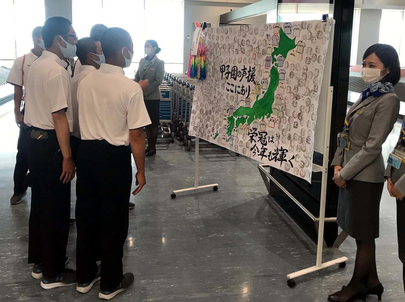 大阪伊丹空港に到着した帯広農の選手たちは、全日空の職員が書いたメッセージボードに見入る（撮影・永野高輔）