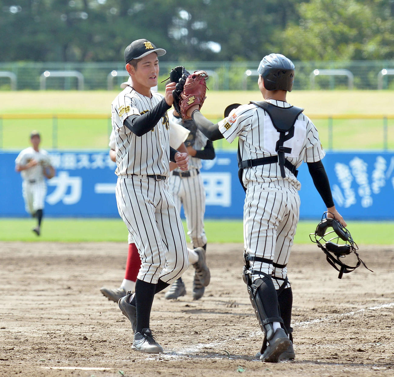 ノースアジア大明桜対秋田商　県大会出場を決めて捕手とハイタッチするノースアジア大明桜・風間（左）