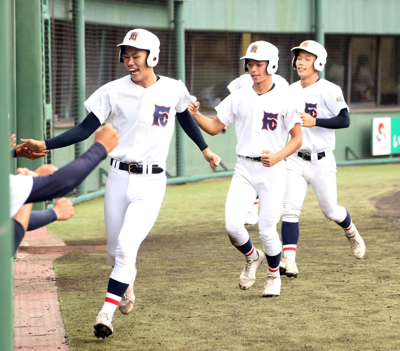 福島商対福島東　3回表福島商2死満塁、佐藤陸の走者一掃中越え適時二塁打で生還しベンチに迎えられる手前から田中、小室、比金（撮影・野上伸悟）