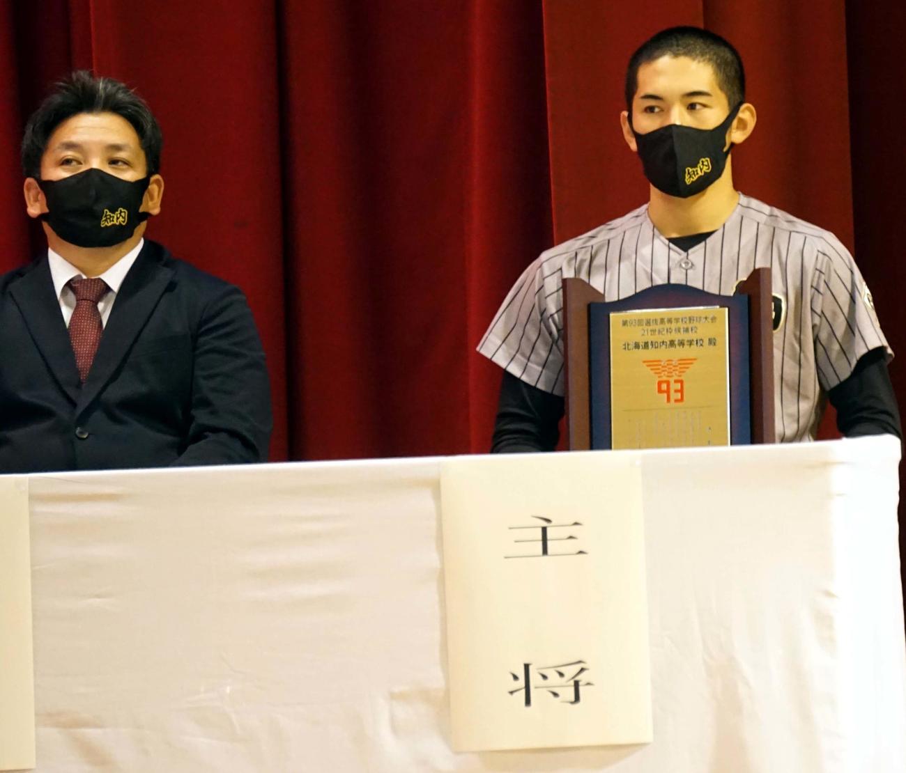 伝達式で記念盾を持つ知内の川村主将（右）と吉川監督（知内野球部提供）