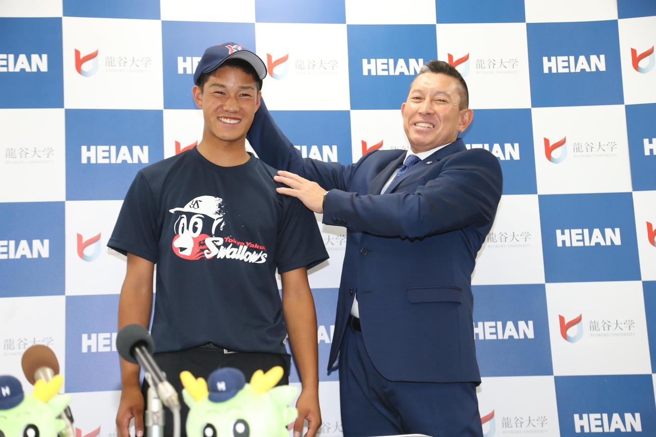 ドラフト指名を受けた高橋奎二にヤクルトの帽子をかぶせる、龍谷大平安・原田英彦監督（2015年10月22日撮影）