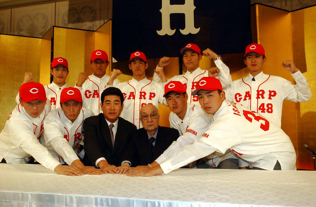 01年12月、広島入団発表で写真に納まる山本翔氏（前列左端）。前列左から3人目が山本監督、同4人目は当時オーナーの松田耕平さん