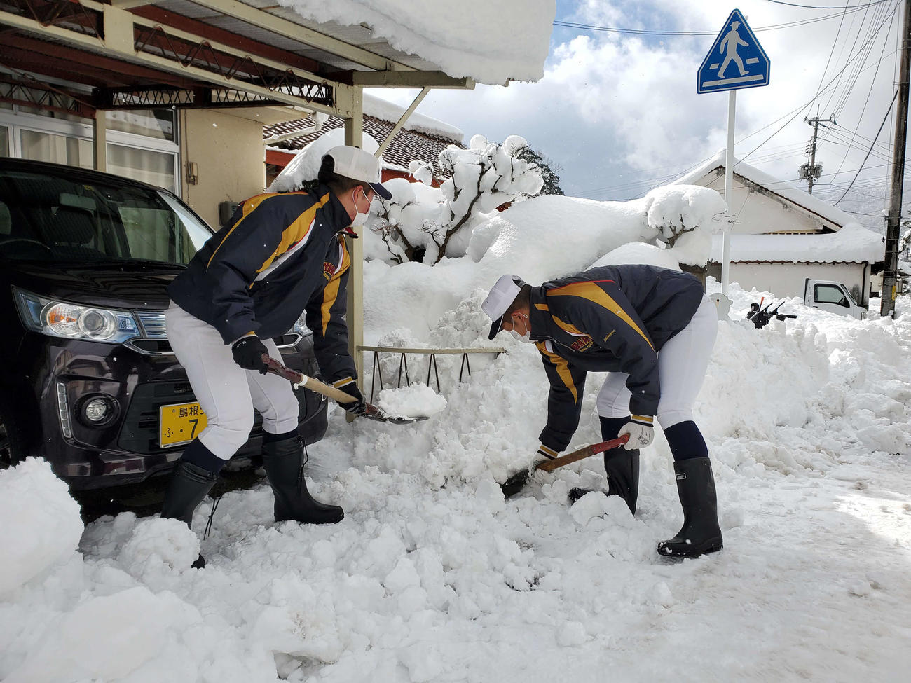 ユニホーム姿で街中に降り積もった雪を除雪する矢上ナイン（チーム提供）