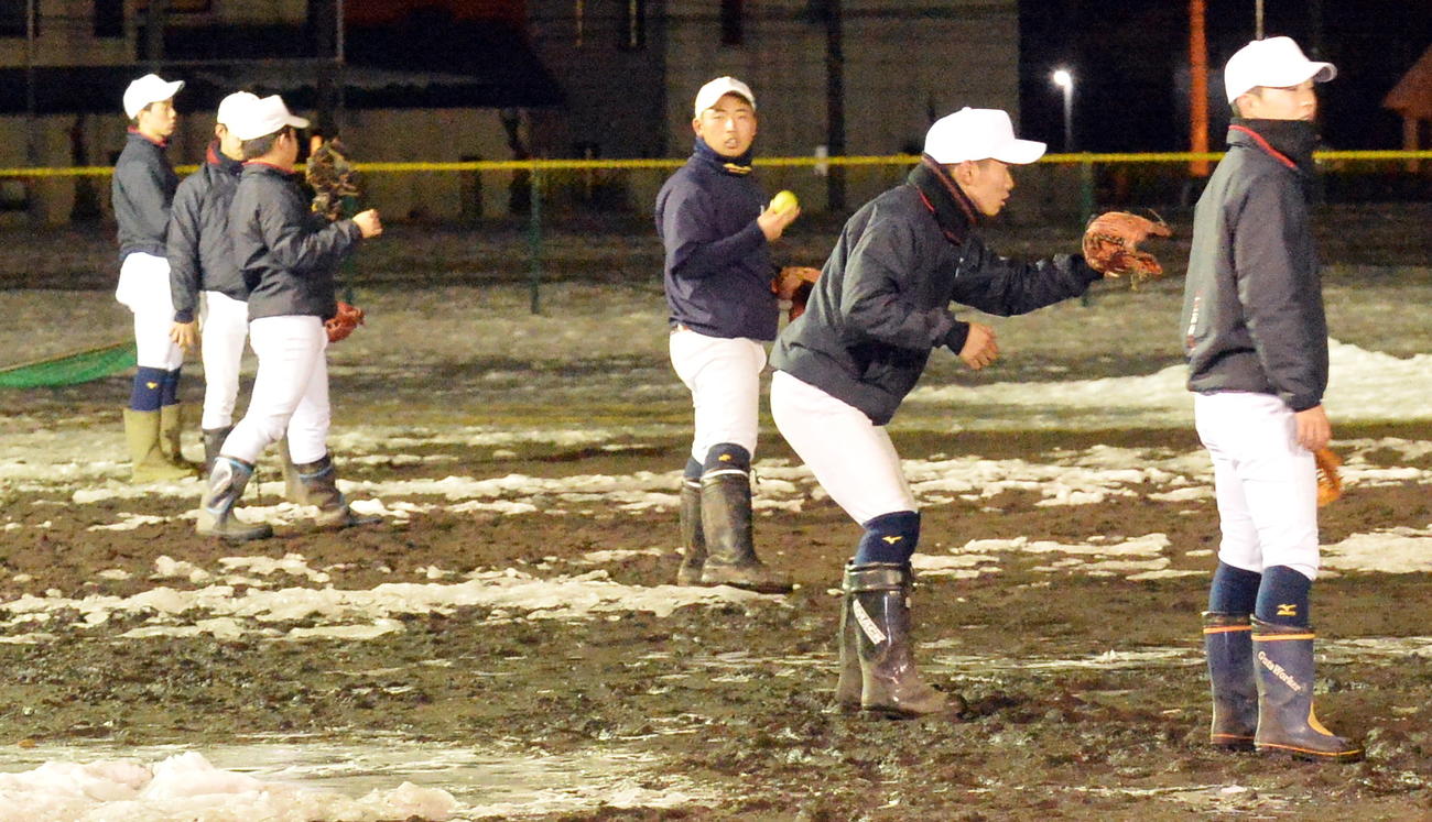 雪が残るグラウンドでキャッチボールを行う八戸西の選手たち（撮影・佐藤究）