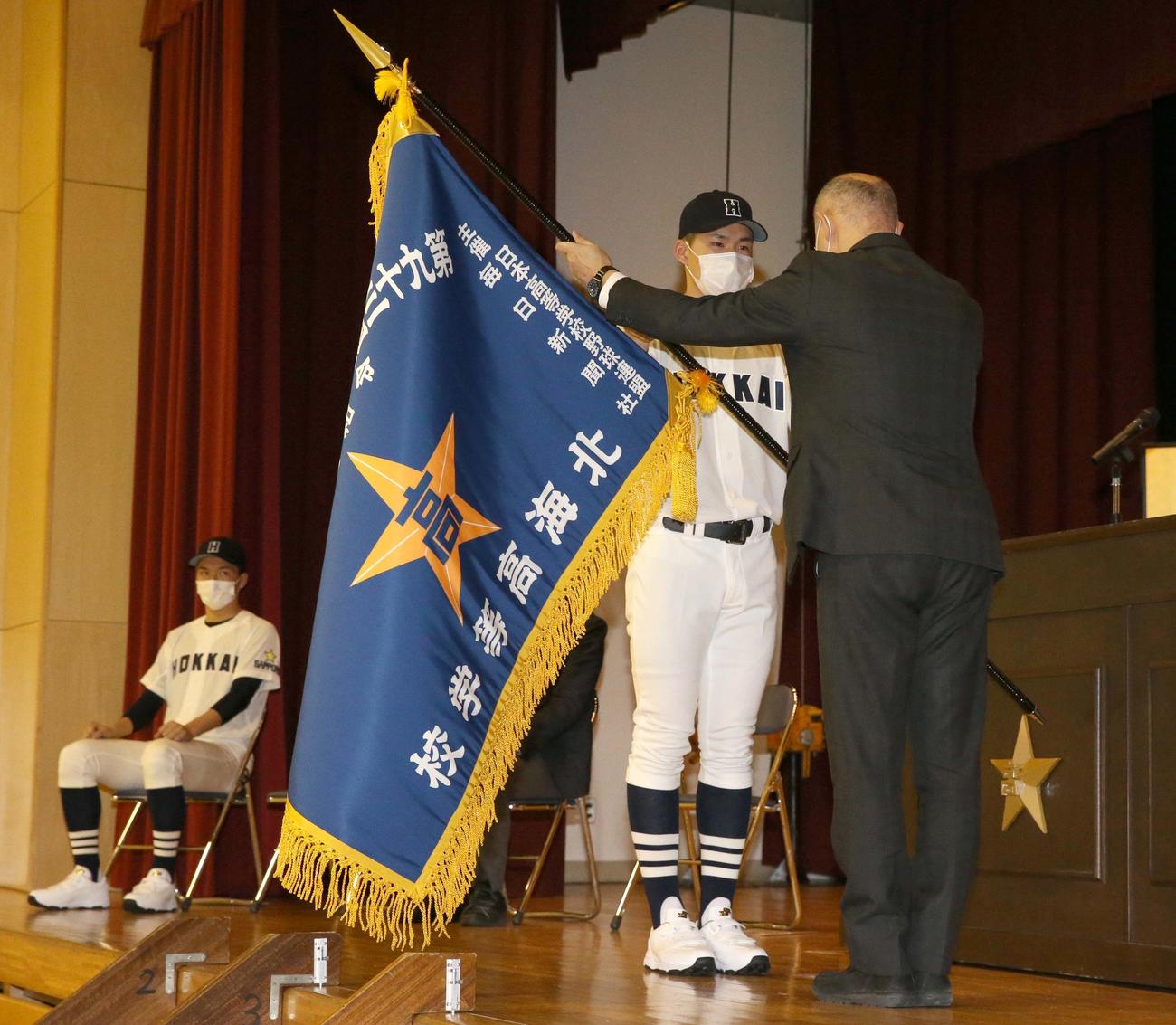 北海の宮下主将（中央奥）は秋山校長から選抜旗を授与される（撮影・佐藤翔太）