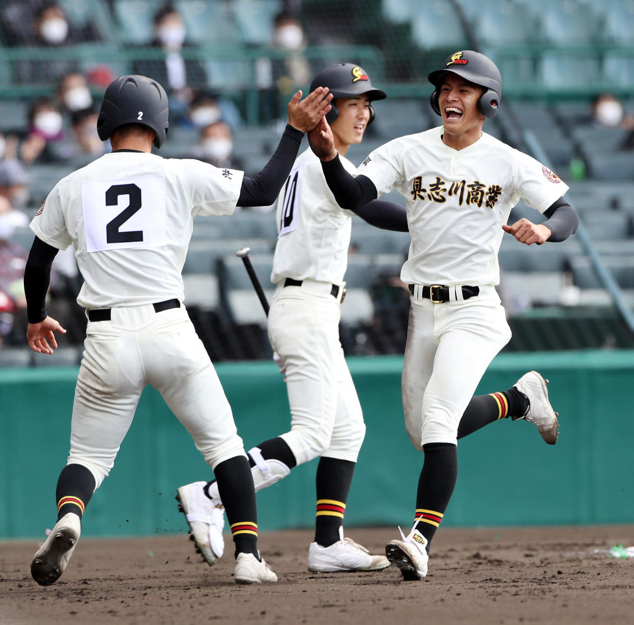 八戸西対具志川商　2回裏具志川商1死二、三塁、二塁走者の知名椋は上原の中前適時打で生還し三塁走者の比嘉と笑顔でタッチする（撮影・加藤哉）
