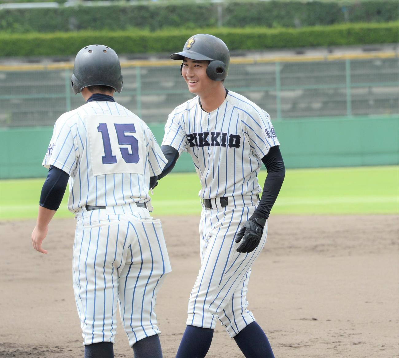 立教新座対狭山経済　2回表立教新座1死一、三塁　左前適時打を放った金子（右）は塁上で笑顔を見せる（撮影・鈴木正章）