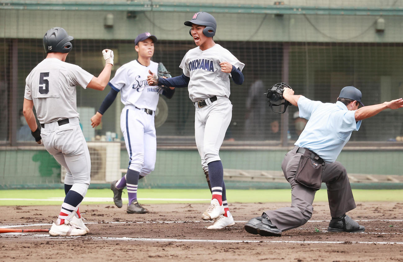 横浜創学館対横浜　1回裏横浜2死一塁、立花祥希の右前打と敵失で先制の生還をし喜ぶ金井。奥は横浜創学館・山岸（撮影・野上伸悟）