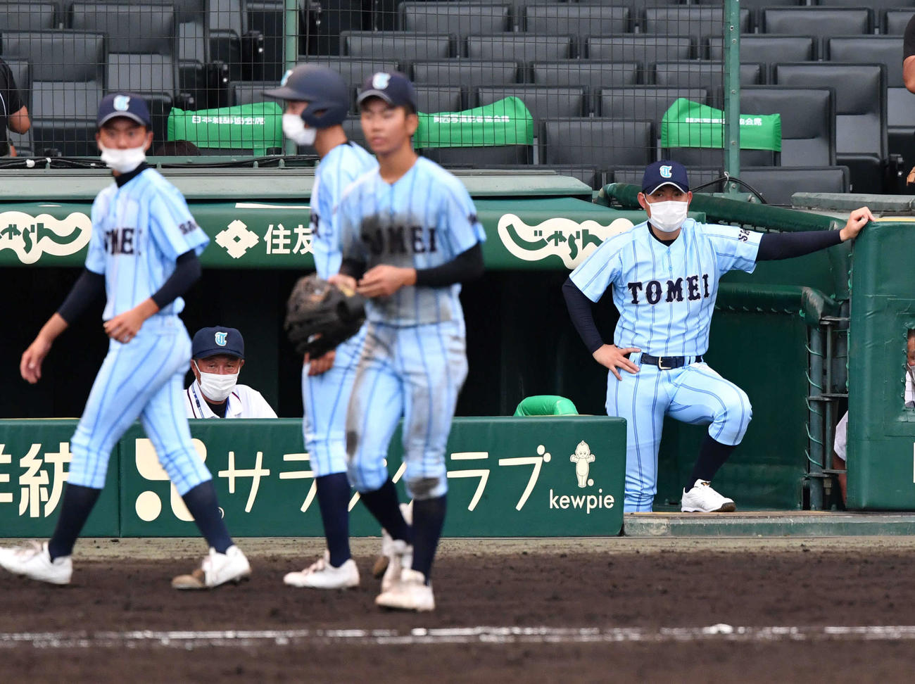東明館対日本航空　8回裏、降板となり左翼の守備位置へ向かう今村（手前左から3人目）をベンチから見つめる東明館・豊福監督（撮影・岩下翔太）