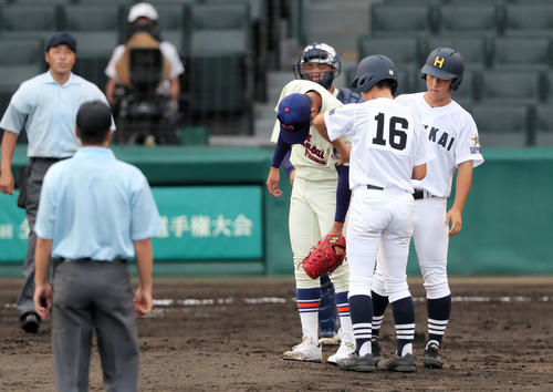 神戸国際大付対北海　5回裏前、捕手の二塁送球練習が左腕に当たった阪上（中央）は北海の選手のアイシングを受ける（撮影・上山淳一）