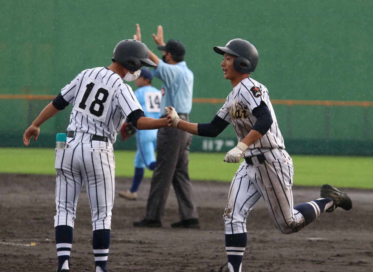 札幌静修対東海大札幌　7回裏東海大札幌無死一塁で送りバントを決め、一塁コーチャーとタッチを交わす石橋（右）（撮影・山崎純一）