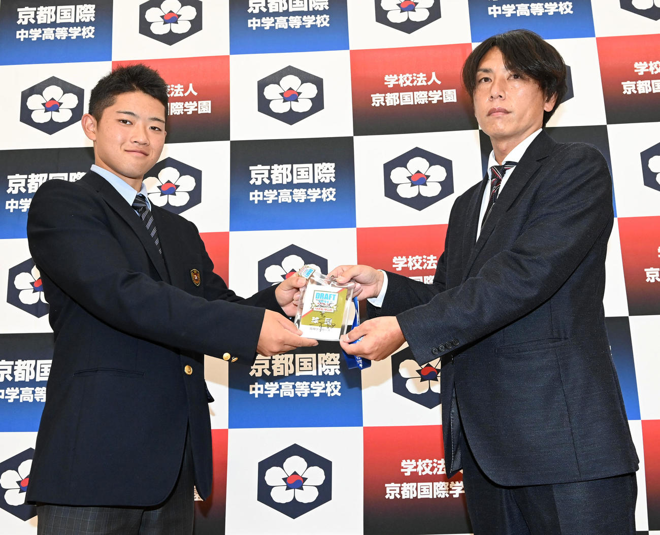 阪神から指名あいさつを受けた京都国際高校の中川（左）は渡辺スカウトから矢野燿大監督のサインが入ったドラフト会議のIDを受け取る（撮影・前岡正明）