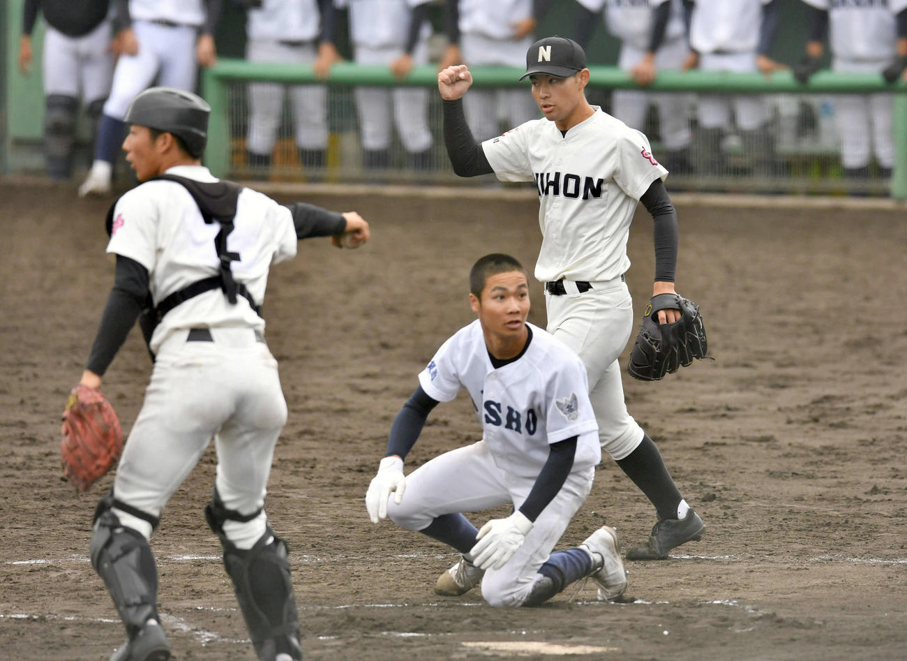 佐賀商対長崎日大　6回表佐賀商1死一、二塁、中島秀の左前安打で二塁から生還を狙った香月（下）を左翼手の平尾が好返球で同点を阻止し、ガッツポーズする種村（撮影・岩下翔太）