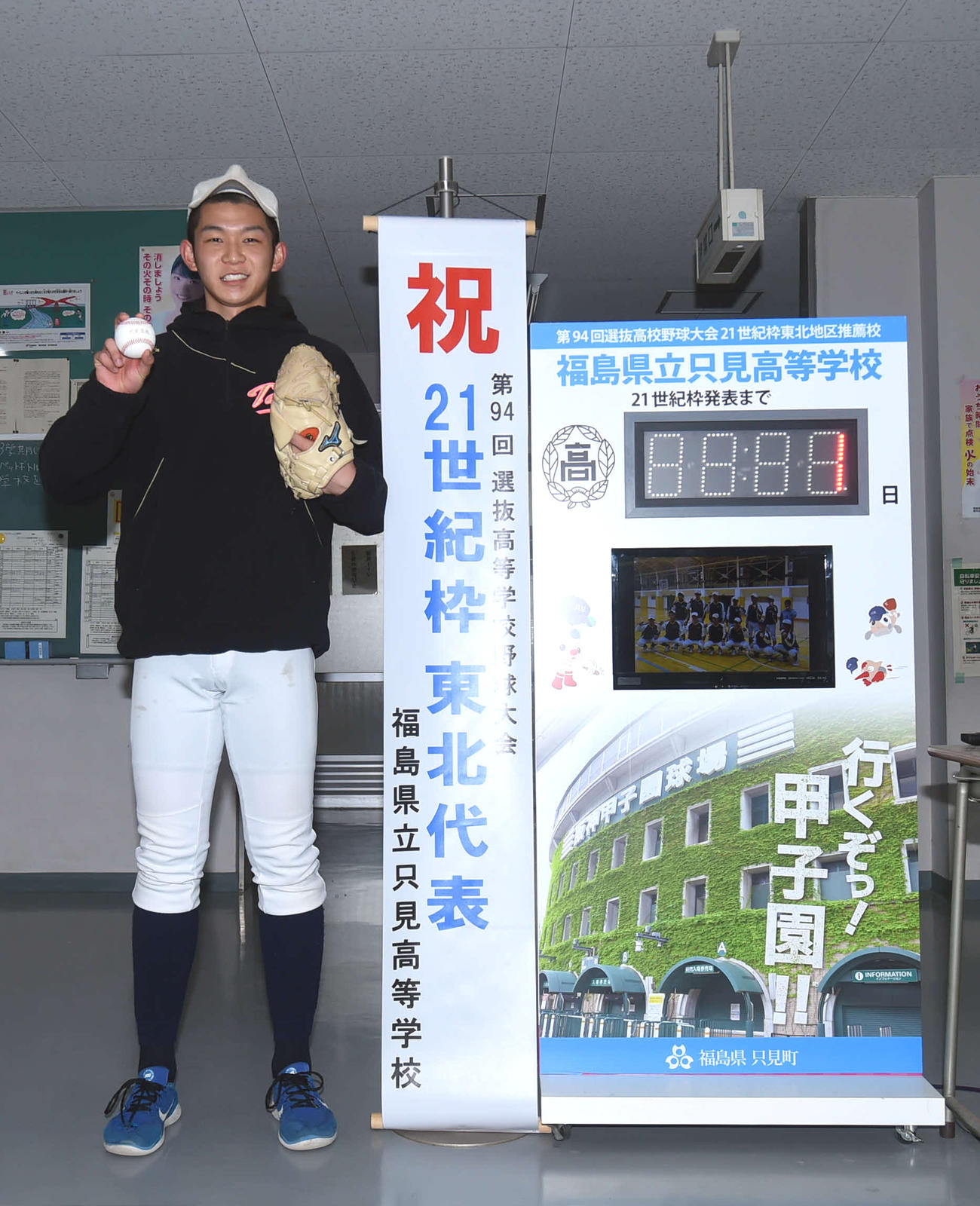 選抜出場校発表を知らせるデイカウンター板の横で笑顔を見せる只見・大竹（撮影・相沢孔志）