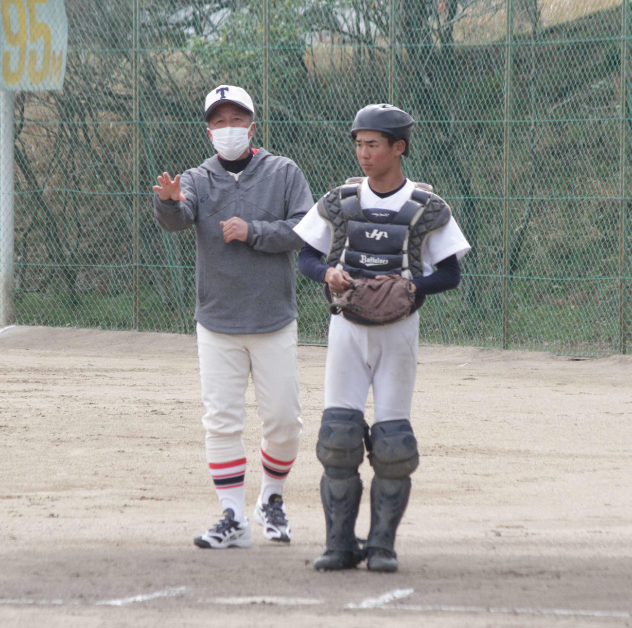 東洋大姫路の岡田龍生新監督が始動し、グラウンドで捕手に助言した