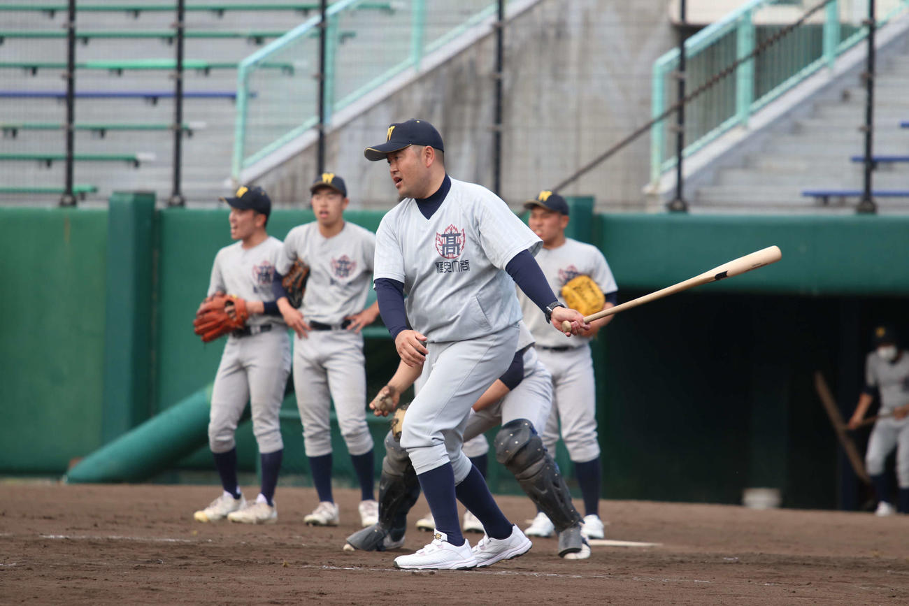 ノックを放つ稚内大谷・本間監督（撮影・山崎純一）