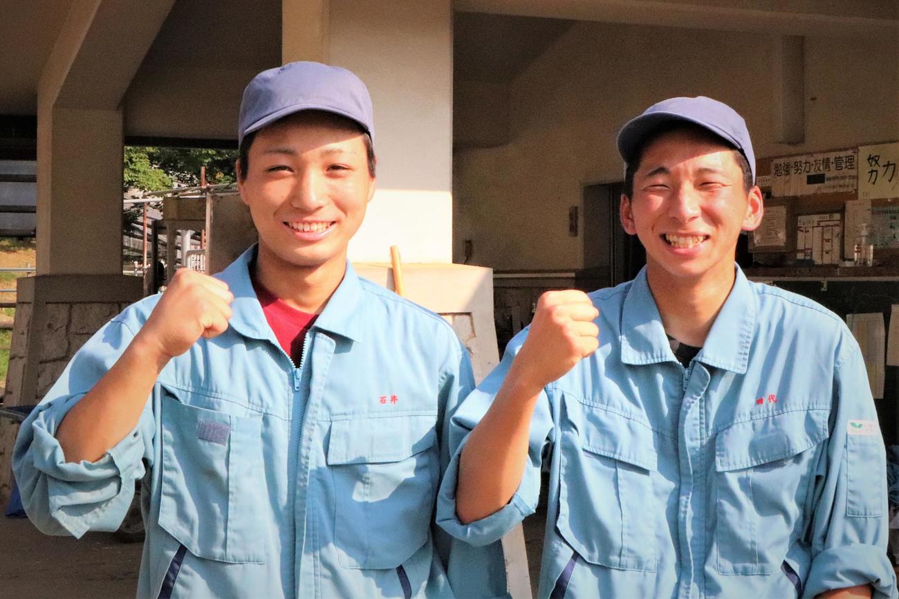 牛舎をバックに作業服姿でポーズをとる瑞穂農芸・石井（左）と田代主将（撮影・藤塚大輔）