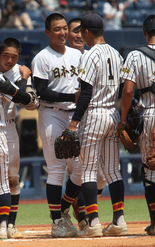健闘をたたえ合い、握手する日本文理・田中(左)と帝京長岡・茨木秀