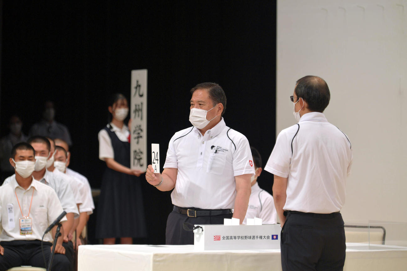 組み合わせ抽選会を欠席した九州学院のくじを代理で引く日本高野連の宝馨会長（代表撮影）