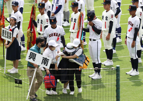 開会式のリハーサル中に倒れ、係員に運び出されるプラカードを持つ生徒(撮影・上山淳一)