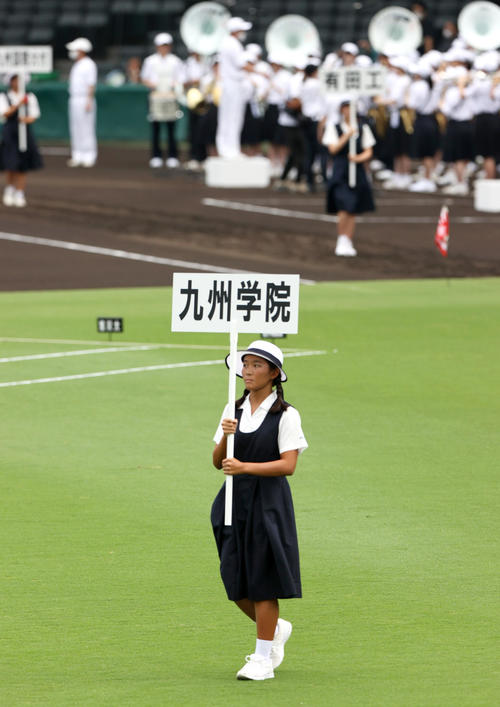 九州学院のプラカードを持ち行進する西宮市立西宮高校の女子生徒（撮影・上山淳一）