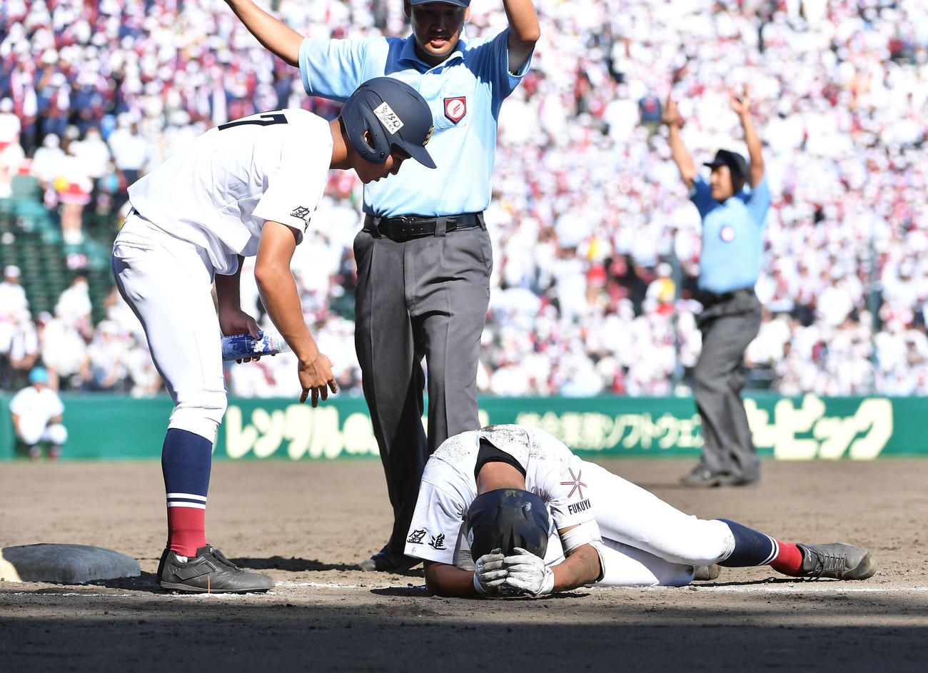 鶴岡東対盈進　5回裏盈進1死一、二塁、投ゴロの時に鶴岡東一塁手の前田と交錯して転倒し、後頭部を強打した神垣はうずくまる（撮影・岩下翔太）