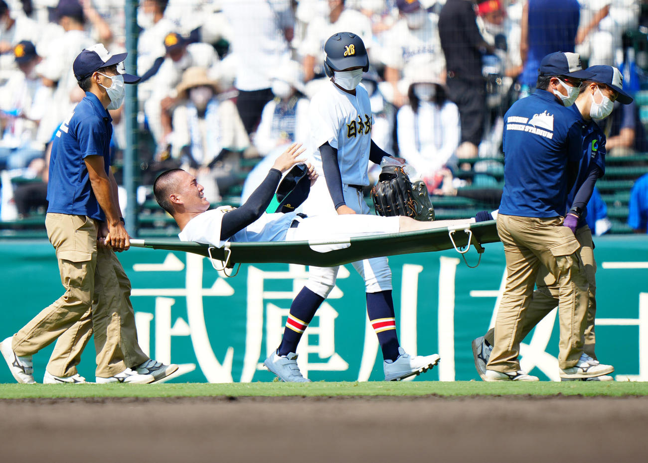 6回表、守備中に足がつった日本文理・玉木（中央）は手当のため担架で運ばれる（撮影・江口和貴）