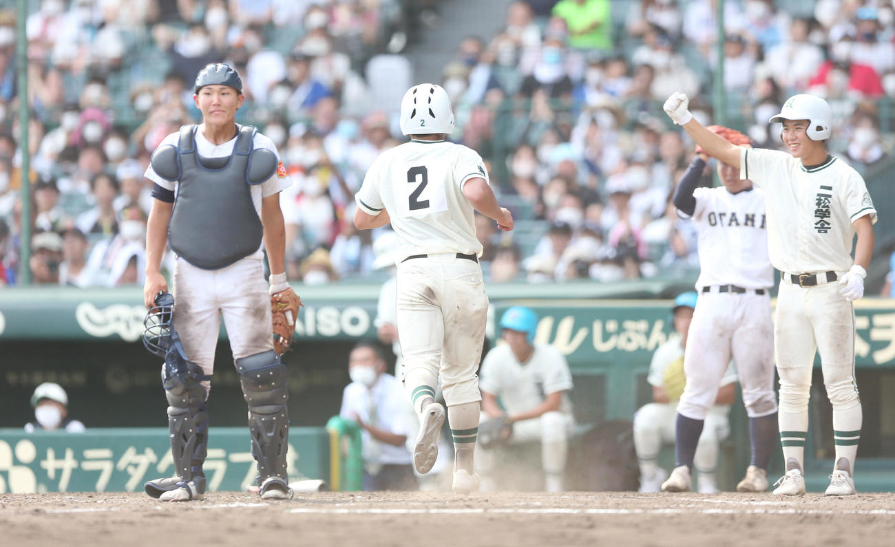 札幌大谷対二松学舎大付　9回裏二松学舎大付1死一、二塁、押切康太郎（中央）が生還し立ち尽くす札幌大谷・佐々木捕手（左）（撮影・宮地輝）