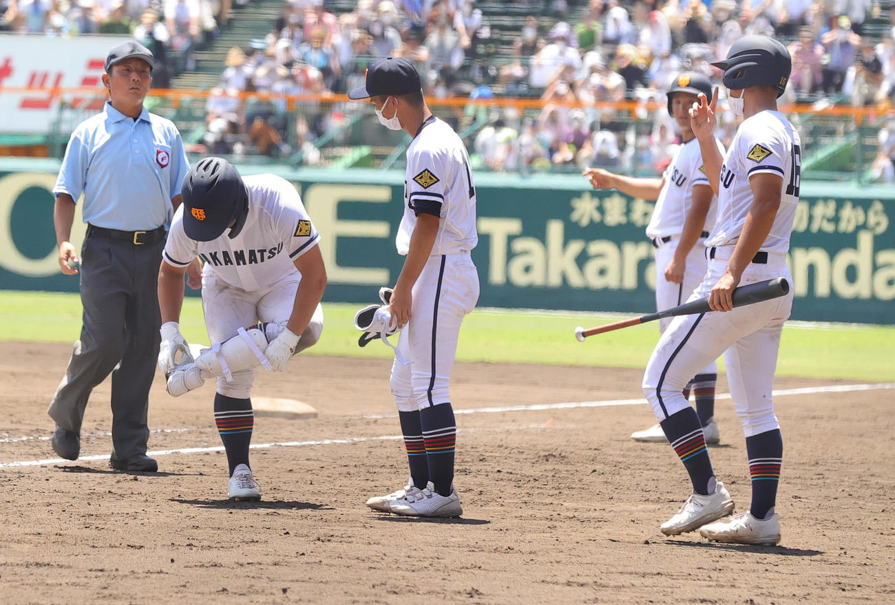 高松商対佐久長聖　8回表高松商1死一、二塁、申告敬遠と言われ一塁に向かった浅野は、取り消しとなり再びレガースなどを装着する（撮影・野上伸悟）