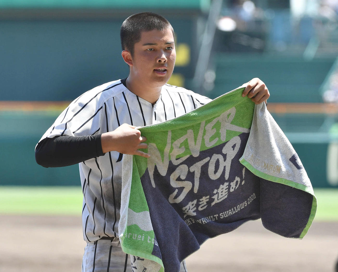 8回裏終了後、2020年のヤクルトのタオルで汗をぬぐう九州学院・村上慶（撮影・岩下翔太）