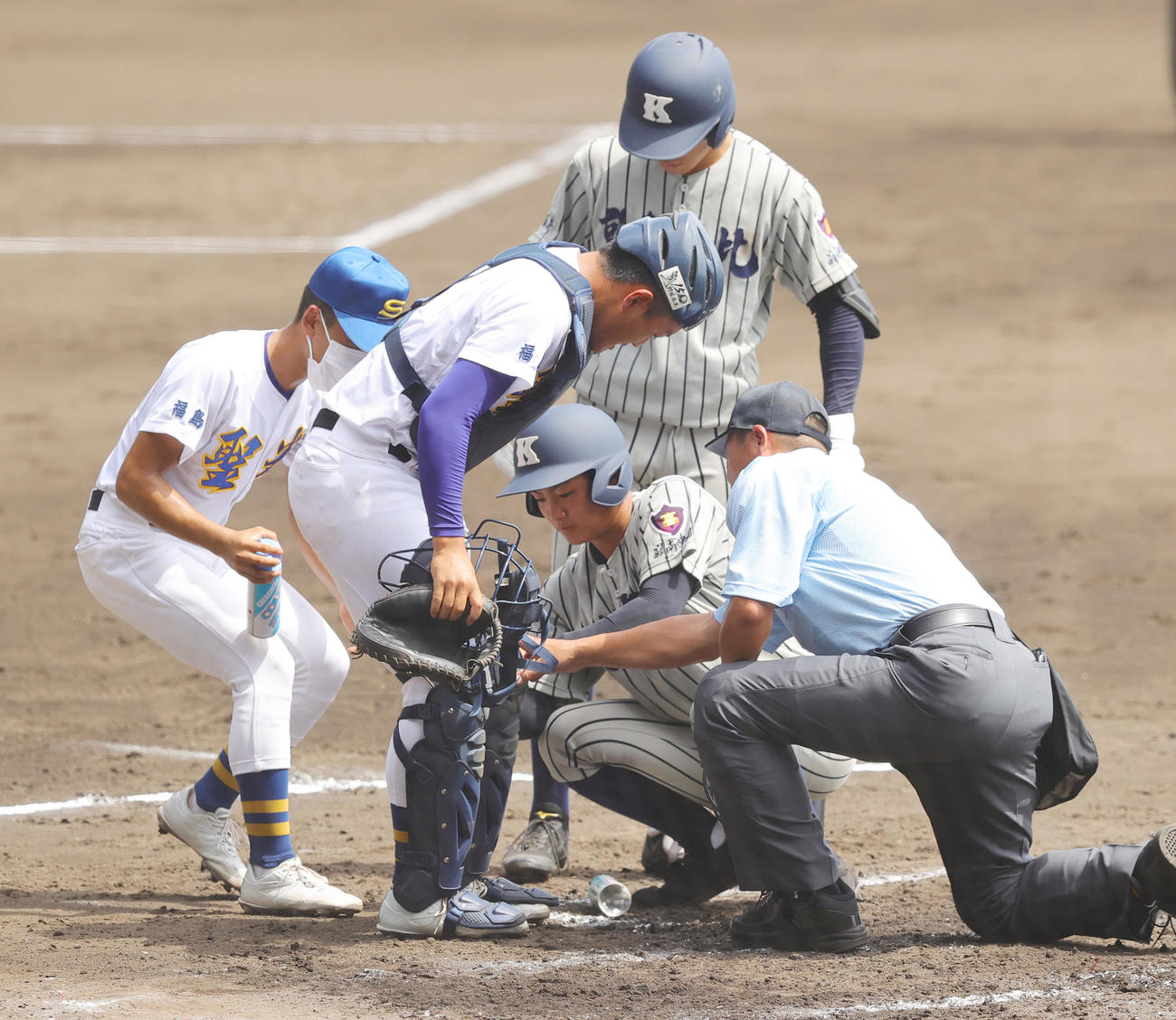聖光学院対敦賀気比　1回裏、左足にボールを当てた聖光学院・山浅捕手（左）の手当を行う敦賀気比三塁コーチャーの伊賀（撮影・野上伸悟）
