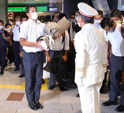 仙台駅に到着し、駅長（右）から花束を受け取る仙台育英・佐藤主将（撮影・野上伸悟）