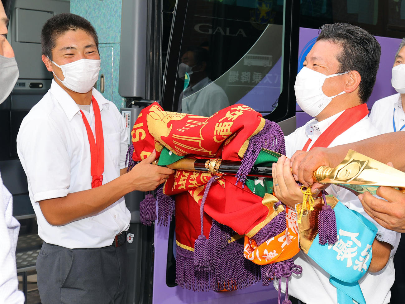 仙台・宮城野校舎での優勝報告会を終えた仙台育英・佐藤主将（左）と須江監督は、バスに乗り込む際に優勝旗を手に笑顔（撮影・野上伸悟）