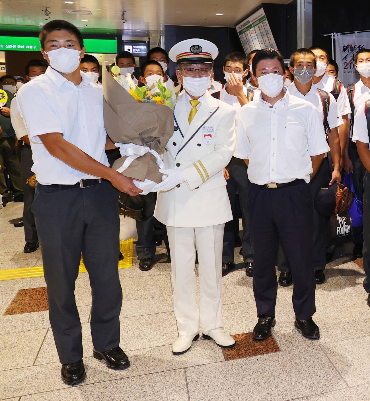 仙台駅に到着し、駅長から花束を受け取る仙台育英・佐藤主将（左）と須江監督（撮影・野上伸悟）