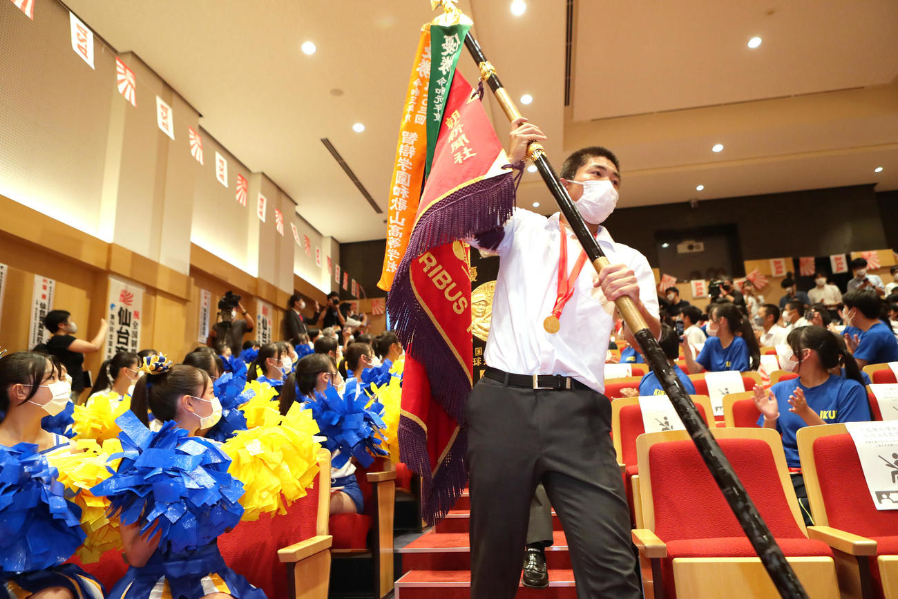 甲子園初優勝を果たし優勝旗を手に報告会に臨む仙台育英・佐藤主将（撮影・足立雅史）