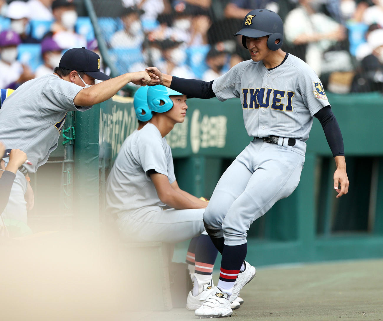 22日の決勝戦の5回、山田の中前適時打で生還した橋本（右）をグータッチで迎える須江監督