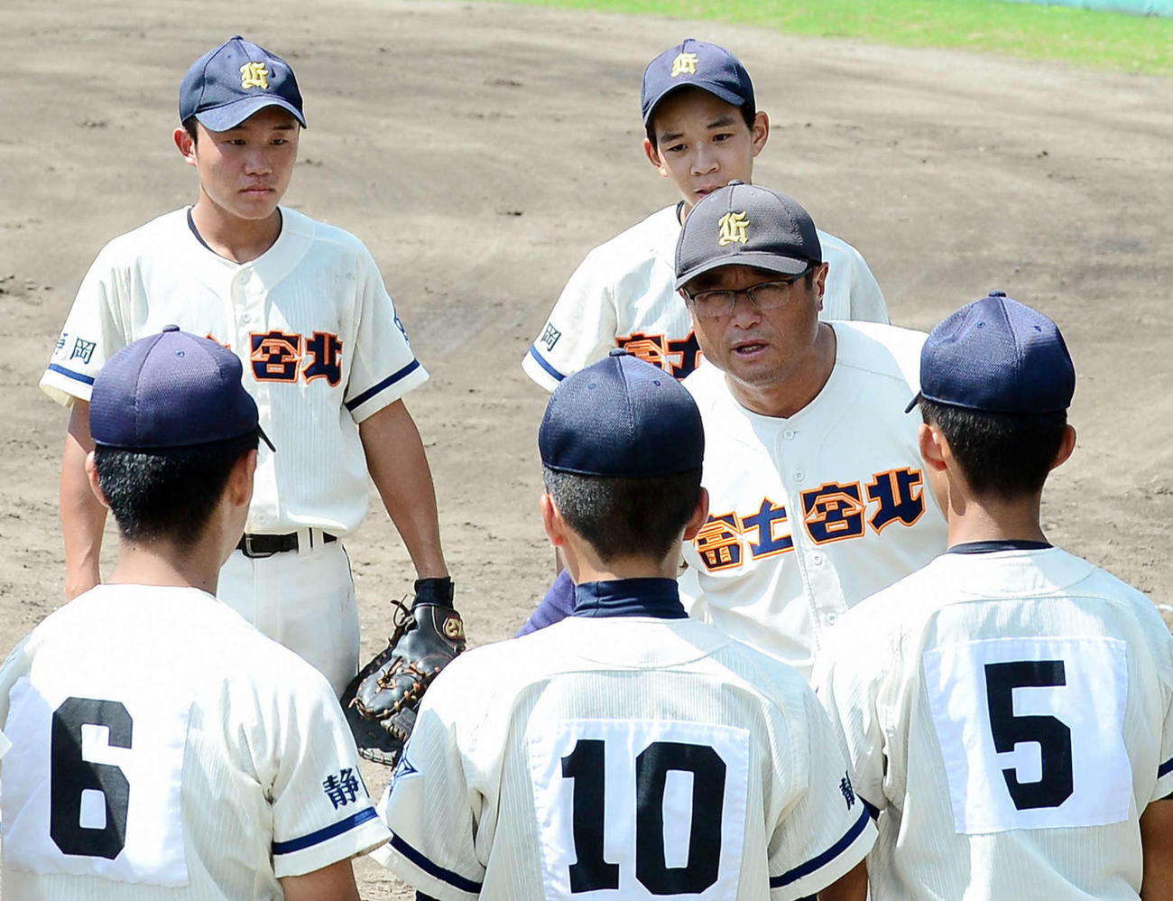 イニング間に選手へ指示を出す富士宮北・塩川監督（右2列目）