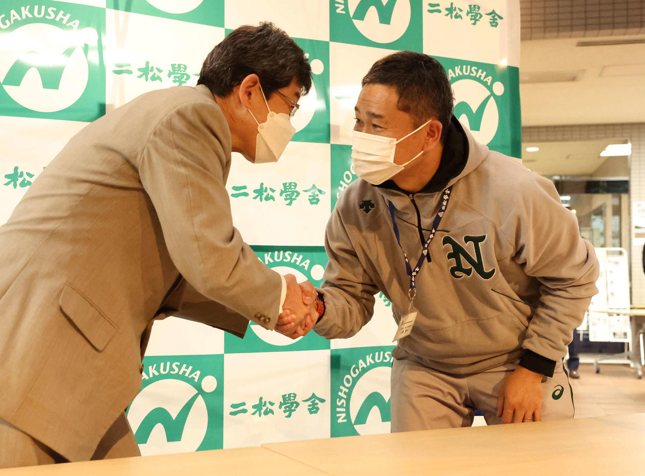 第95回選抜高校野球大会に選ばれて握手する二松学舎大付の鵜飼校長（左）と立野部長（撮影・丹羽敏通）