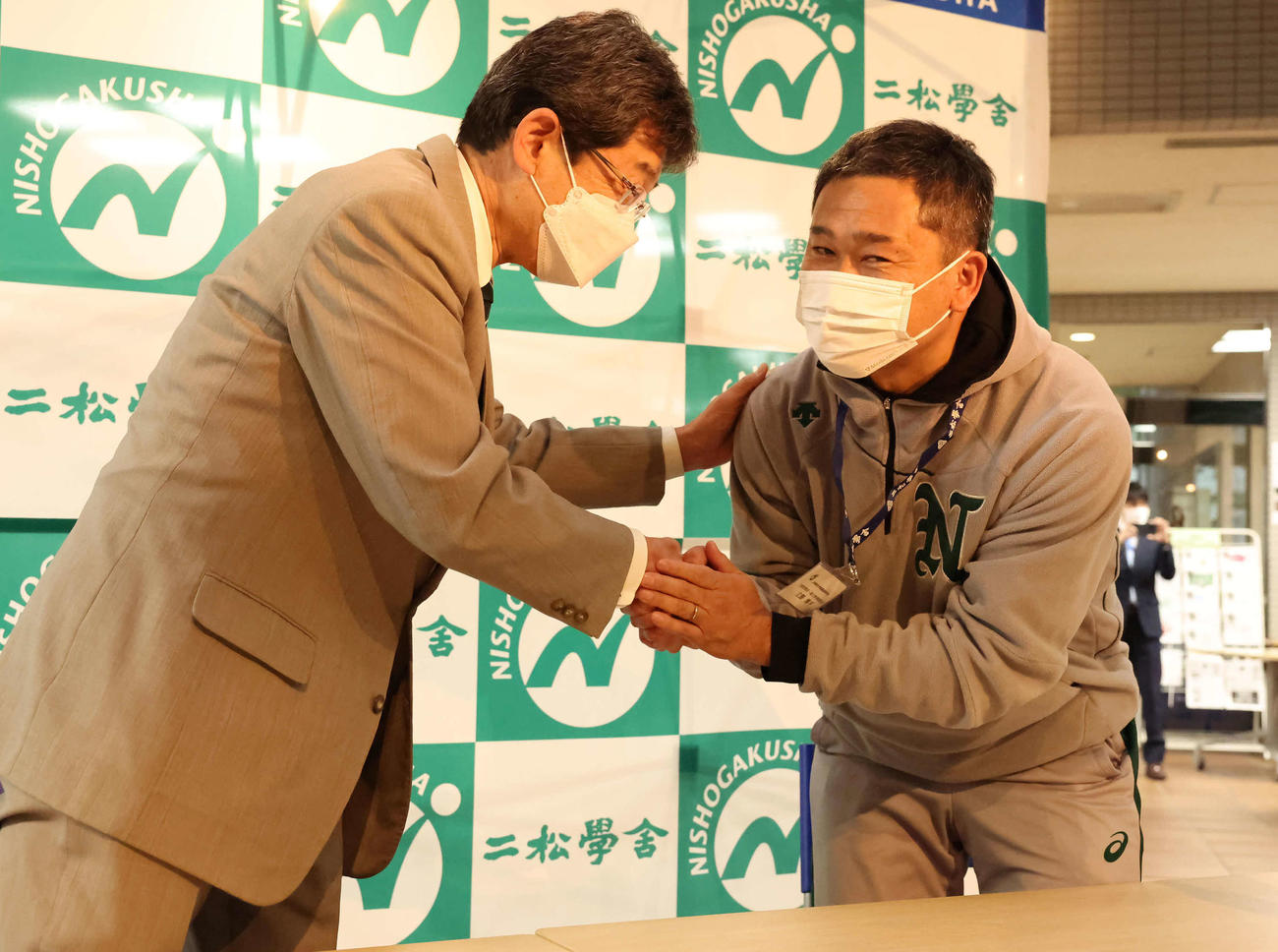 第95回選抜高校野球大会に選ばれて握手する二松学舎大付の鵜飼校長（左）と立野部長（撮影・丹羽敏通）