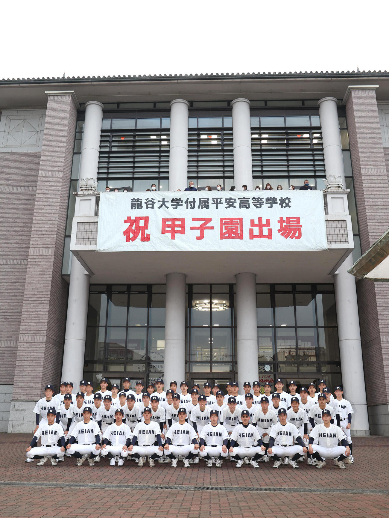 祝甲子園出場の横断幕を背に記念撮影に納まる龍谷大平安ナイン（撮影・白石智彦）