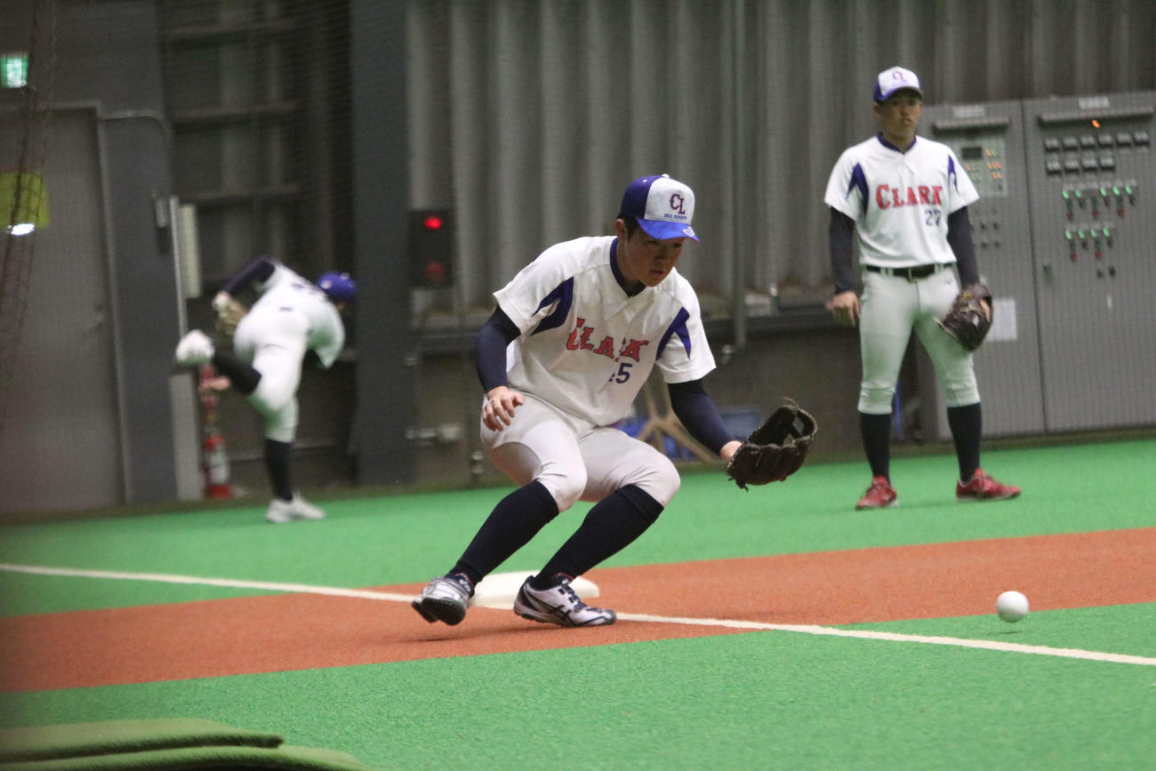 三塁でノックを受けるクラーク・中村（撮影・山崎純一）